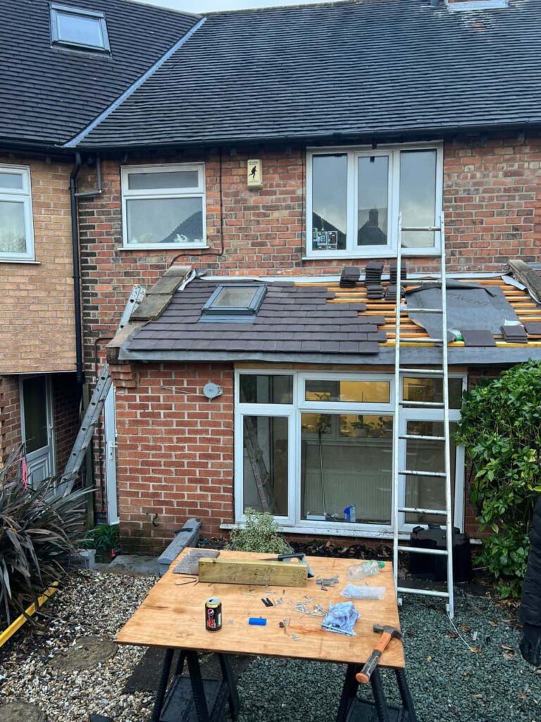 This is a photo of a roof extension that is having new roof tiles installed. This is a photo taken from the roof ridge looking down a tiled pitched roof on to a flat roof. Works carried out by Horley Roofing Repairs