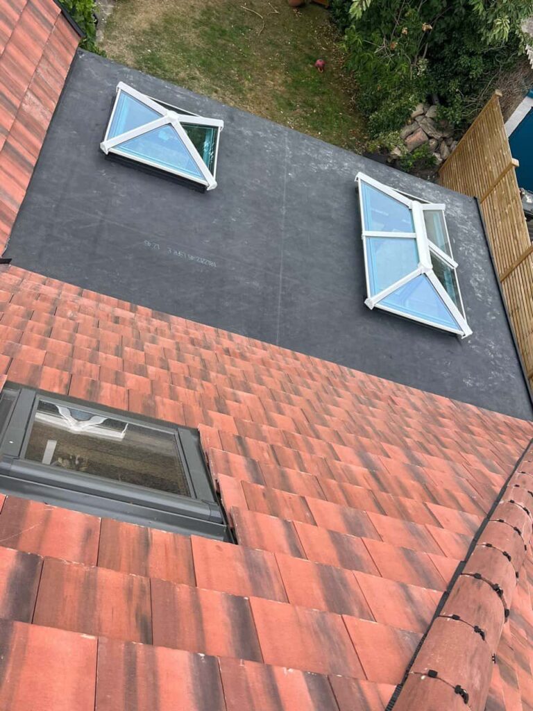 This is a photo taken from the roof ridge looking down a tiled pitched roof on to a flat roof. Works carried out by Horley Roofing Repairs